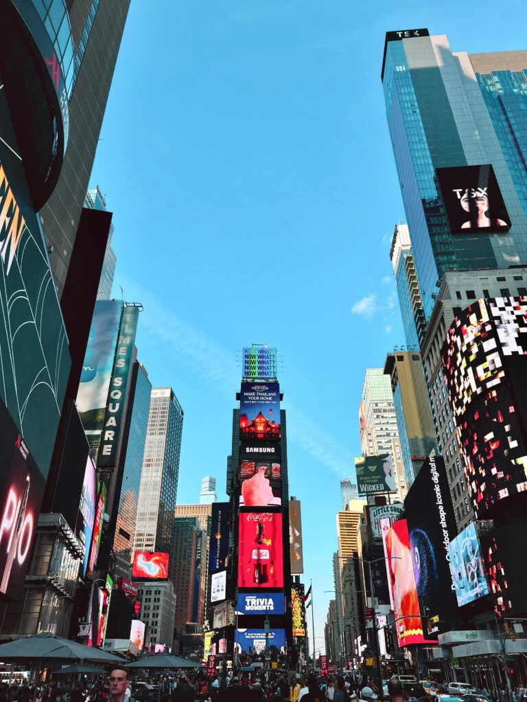 "Vibrant scene of Times Square in Manhattan, illuminated by bright neon lights and large digital billboards, bustling with crowds of tourists and locals, showcasing the iconic energy of the city."