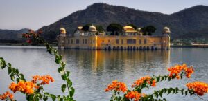 "Golden Jal Mahal palace in Rajasthan, surrounded by serene lake waters and mist-covered Aravalli hills in the background."