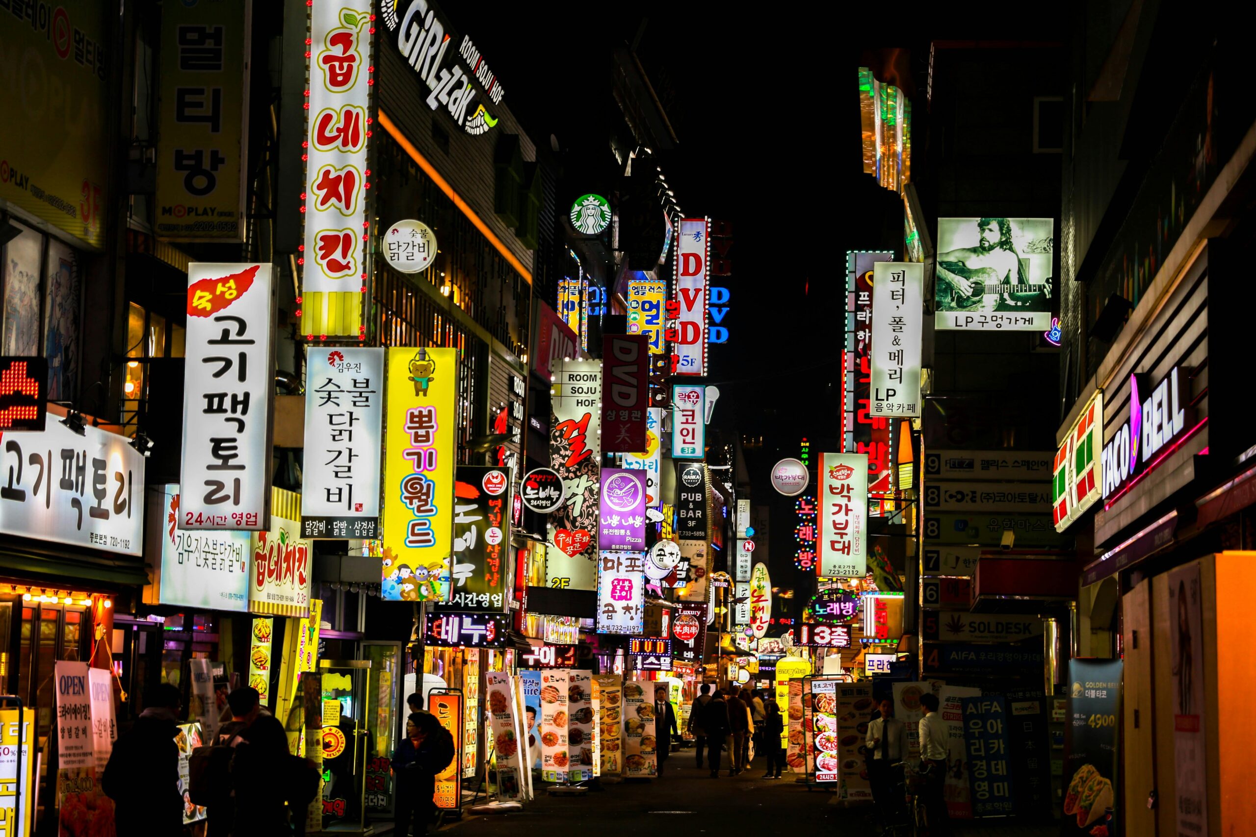 "Vibrant South Korean market bustling with colorful displays, neon hoardings, and lively street vendors showcasing local goods and produce."